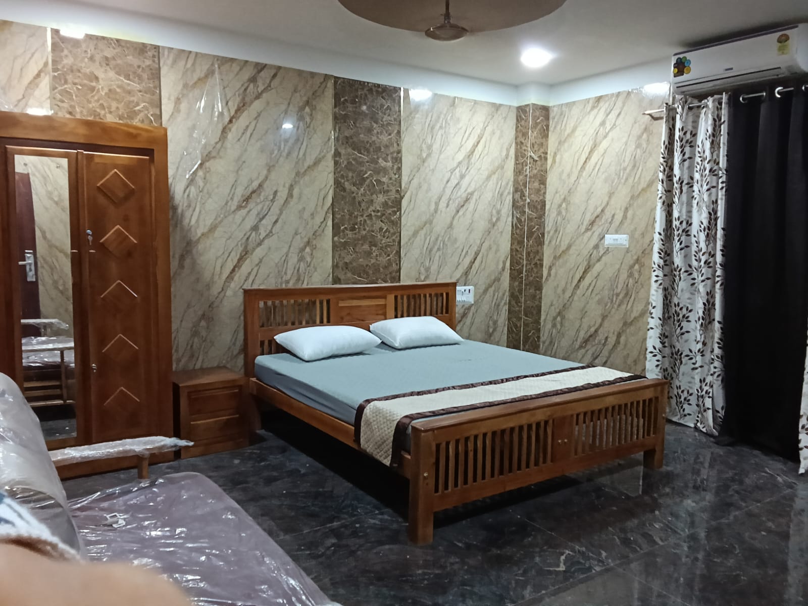 Luxury AC room with wooden double bed and marble finish walls